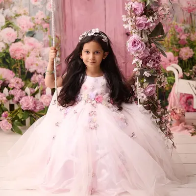A fairytale moment comes to life with this portrait of a young girl on a swing adorned with pink flowers. Our elaborate studio setups are designed to make every child feel like they are in a magical story.