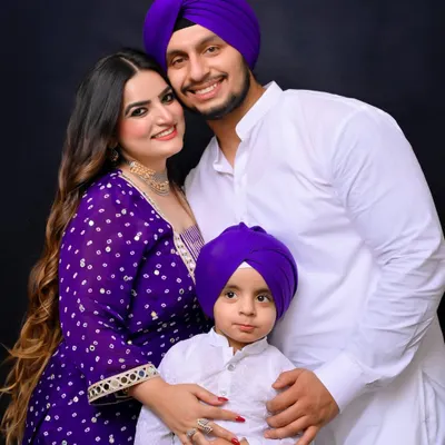 A beautiful studio portrait of a Sikh family, dressed in coordinated white and purple traditional attire. The image radiates warmth and togetherness, showcasing a classic family photograph.