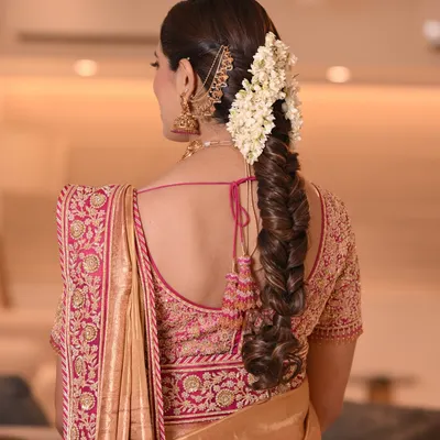 A stunning example of a traditional South Indian bridal braid. This fishtail braid is adorned with fresh jasmine flowers and gold accessories, creating a timeless and elegant look.