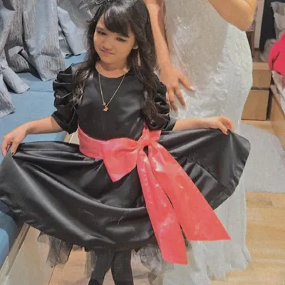 Our client Ayana looks absolutely adorable in her custom MYME party dress. The design features a classic black silhouette with a statement pink satin bow, perfect for birthdays and special events.
