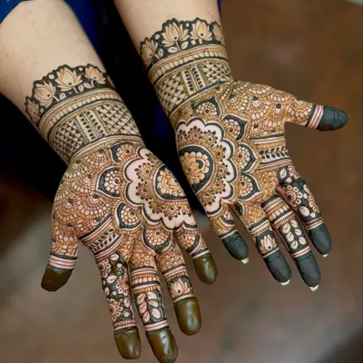 A beautiful and dense mehendi design for a housewarming ceremony. This style features traditional mandala art on the palm with intricate patterns covering the fingers and wrist.