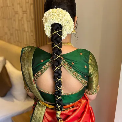 A detailed view of a classic South Indian bridal hairstyle. This traditional braid is intricately woven with gold thread and adorned with a circle of fresh jasmine (gajra) for a timeless and elegant finish.