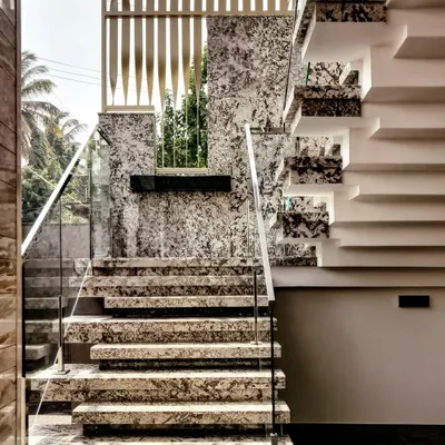 The exterior staircase at 'House Reversed' is a statement piece. I chose a combination of Bianco and Blue Pearl granite for the treads and risers, paired with a sleek glass handrail to create a modern and luxurious feel.