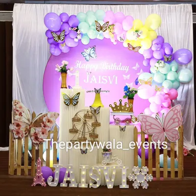 A stunning butterfly-themed party with a pastel rainbow balloon arch and large, colorful butterfly cutouts.