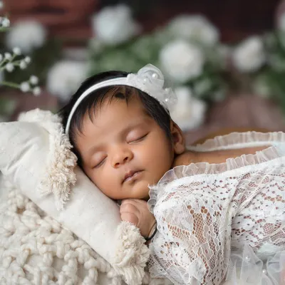 A close-up of a sleeping newborn, dressed in delicate white lace and a pearl headband. I focus on capturing their angelic features and peaceful expressions.