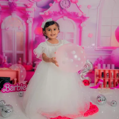 Our two-year-old Barbie princess holding a balloon, looking absolutely radiant in her beautiful white gown against the pink dollhouse backdrop.