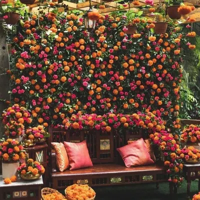 A stunning Haldi backdrop made entirely of a dense wall of orange and pink marigolds. This is a classic choice that always looks incredible in photos.