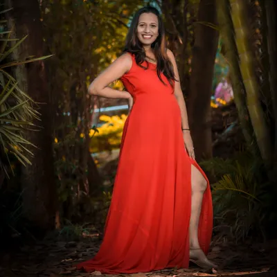 A stunning solo portrait in a vibrant red gown. The thigh-high slit adds a touch of glamour, perfect for a mom-to-be who wants to feel confident and beautiful.