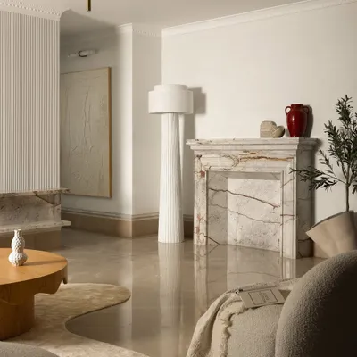 A view of the Ecru Maison living room, where a sculptural marble fireplace and a fluted floor lamp add layers of texture. We focused on a mix of organic forms and natural materials like oak and boucle to create a space that feels both modern and timeless.
