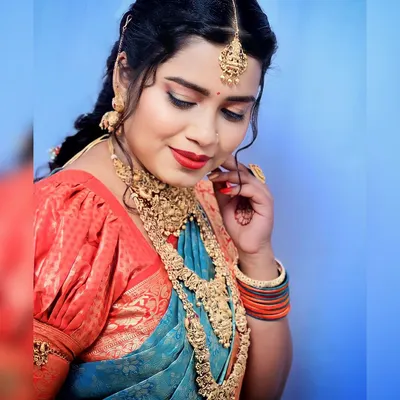 A stunning bridal photoshoot look. This features dramatic eye makeup, a bold red lip, and elaborate temple jewelry, showcasing a high-fashion bridal style.