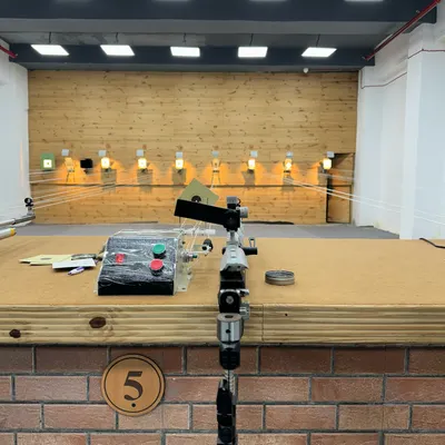 Your lane is ready. This is a shooter's view of our professional setup, featuring an air pistol and the electronic target system you will train with from day one.