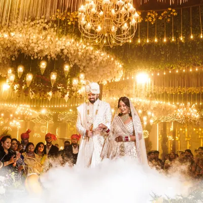 A breathtaking entry for a fairytale wedding. The couple walks through a cloud of smoke under a grand chandelier, a perfect example of the cinematic and grand wedding moments I love to capture.