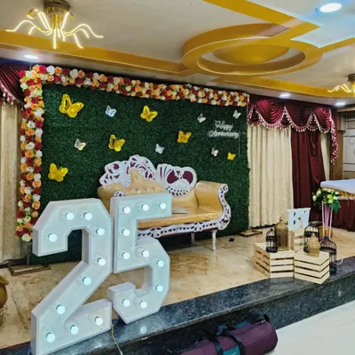 This is another view of the 25th-anniversary stage, showing how the elements come together in a larger venue. The combination of the green wall, floral arrangements, and prominent light-up numbers creates a complete and festive look.