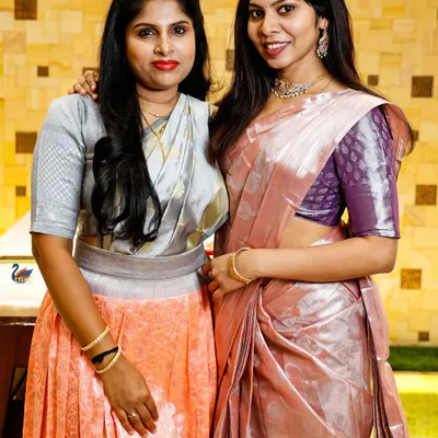 A portrait of two women in elegant sarees at a family event. I enjoy capturing photos of guests enjoying the celebration.