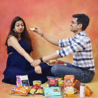 A funny and relatable take on pregnancy cravings. This playful studio shot captures the couple surrounded by snacks, adding a touch of humor to their maternity photoshoot.