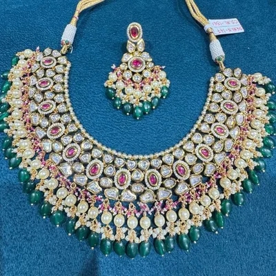 This beautiful kundan necklace set is a perfect example of fine making. It features high-quality kundan stones accented with ruby-red centerpieces and finished with elegant green beads and pearls.
