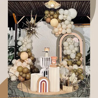 A complete boho teddy bear setup featuring a beautiful balloon arch in earthy tones, pampas grass details, and custom rainbow props for a warm, modern aesthetic.