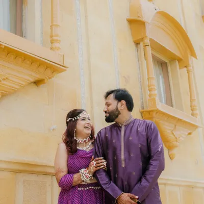 A candid moment between the couple against the beautiful architecture of the Chokhi Dhani Palace Hotel, capturing a natural, happy interaction.