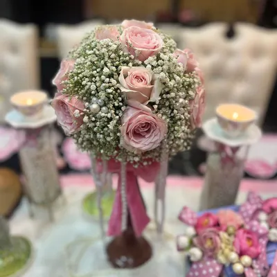 This is a centerpiece I created for a coquette-inspired theme. A lush bouquet of pink roses and baby's breath is accented with cascading pearls and a pink ribbon, creating a look of vintage romance and playful elegance.