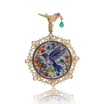 My hummingbird micromosaic pendant, a piece that captures a fleeting moment of nature's beauty. The bird and flowers are meticulously crafted from tiny glass tiles, set in an 18k gold and diamond filigree frame with a dangling emerald.
