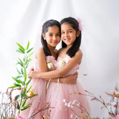 Two of a kind. These twin sisters share a sweet hug in their beautiful pink dresses, surrounded by a lovely floral setup for their 7th birthday photoshoot.