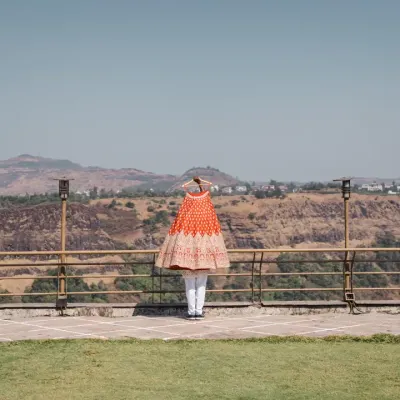 The bride's stunning orange lehenga hangs against the vast, mountainous landscape. This artistic shot creates a beautiful contrast and builds anticipation for her bridal look.