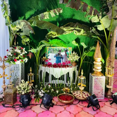 A traditional baby shower setup with a backdrop of lush banana leaves. The decor includes authentic elements like brass lamps and floral arrangements, creating a classic South Indian vibe.