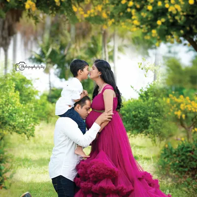 This shot captures pure family joy in our garden setting. The father kisses his wife's baby bump while their son kisses her, all framed by beautiful yellow flowers. The flowing pink gown adds a touch of elegance to this candid moment.