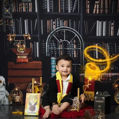 This little wizard is sitting proudly in his magical library. The detailed Harry Potter themed setup includes iconic books, a Hedwig prop, and warm lighting to create an authentic and enchanting scene for a first birthday photoshoot.