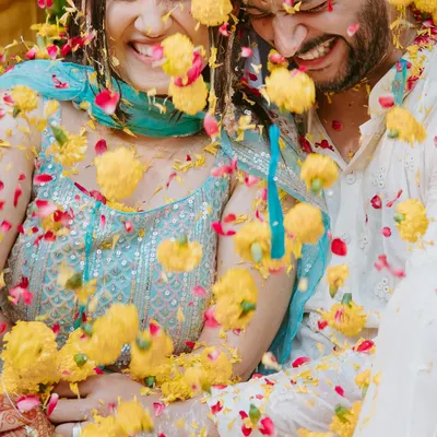 The moment of impact. A couple shares a laugh as they are showered with marigold and rose petals during their vibrant Haldi ceremony in Chandigarh.