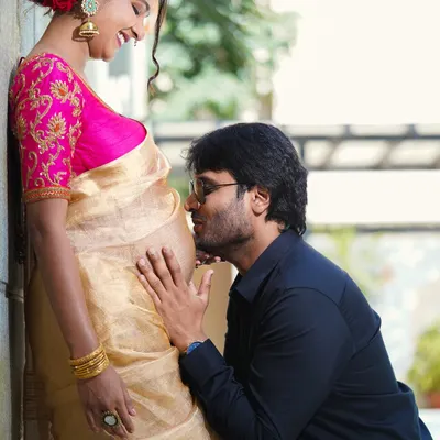 A close-up, colorful maternity portrait. The partner kissing the baby bump is a classic expression of love and excitement for their coming child.