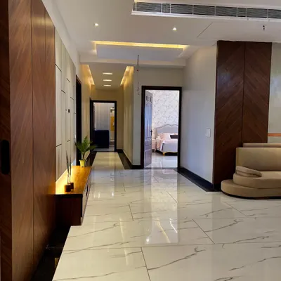 A view down the hallway of a recently completed apartment. The combination of polished marble-finish floors, warm wood paneling, and strategic ceiling lights creates a long, elegant corridor that feels both modern and inviting.