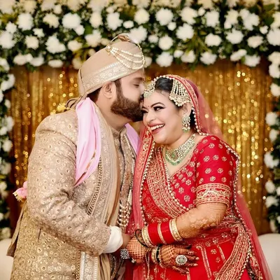 A perfect candid moment of pure happiness. The groom's affectionate kiss and the bride's joyful laugh are what candid wedding photography is all about.
