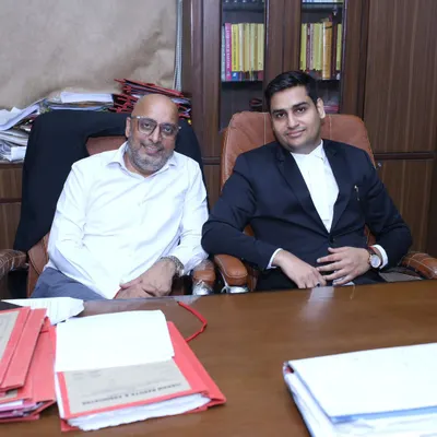Seated in my chamber with a senior colleague, surrounded by case files. This is where we collaborate and plan the best course of action for complex legal matters.