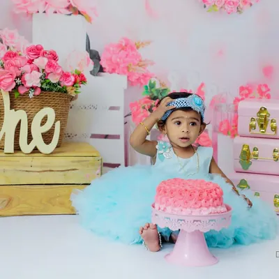 A princess and her cake! This little girl looks a bit unsure about the pink cake in front of her, making for a cute and funny moment during her first birthday cake smash photoshoot.
