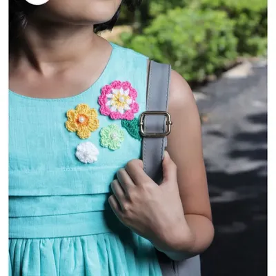 A beautiful close-up of a floral arrangement patch on a girl's aqua blue dress. The different flower sizes and colors, some with pearl centers, create a lovely bouquet effect.