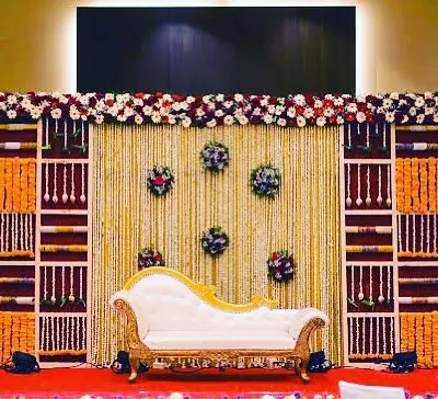 Beyond balloons, we also create traditional stage decorations for formal events. This setup features a backdrop of rich fabrics and intricate floral arrangements with marigolds and roses, perfect for cultural ceremonies or formal receptions.