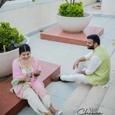 A relaxed moment during a Mehendi ceremony. The couple is sitting together on a rooftop, enjoying the quiet moments before the big celebrations begin.