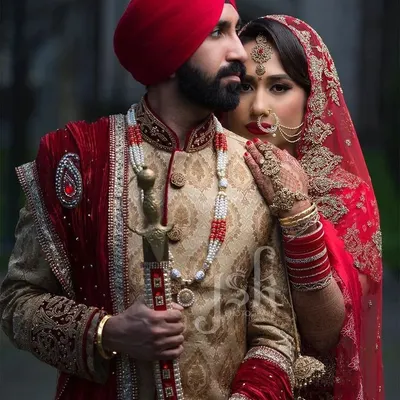 A powerful and regal look for a Sikh wedding ceremony. The bride's red lehenga and the groom's beige brocade sherwani with a matching red pagri (turban) are available for rent as a coordinated set.