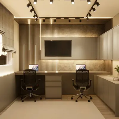 A highly functional home office designed for two people. This setup includes a long shared desk, ergonomic chairs, and ample overhead and lower cabinet storage, all illuminated by modern track lighting.