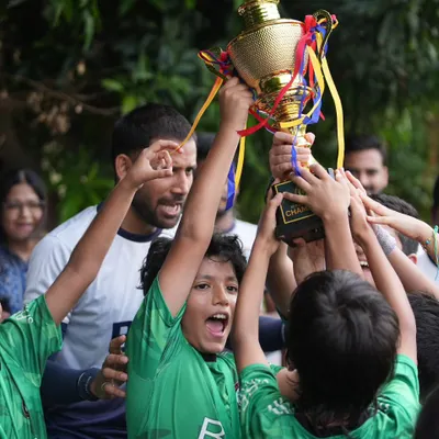 The roar of champions. This moment captures the pure elation of our young team as they lift the trophy, a testament to their collective effort.