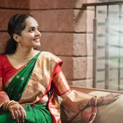 A beautiful bridal portrait capturing a moment of quiet reflection, with soft window light highlighting her joyful expression and traditional green saree.