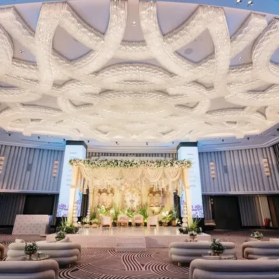 The magnificent ballroom transformed into a serene palace. The stage, with its ivory and gold jharokhas, stands as the focal point, perfectly complemented by the room's grand architecture.