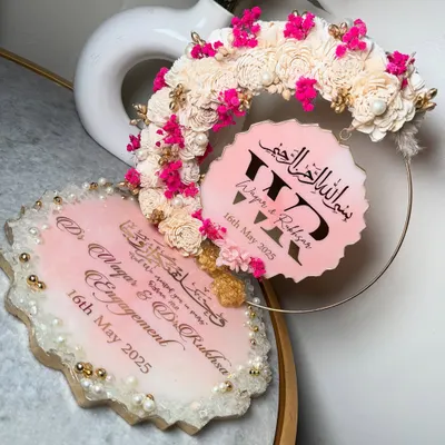 A beautiful pink and white resin ring platter for an engagement. This set includes a main tray for the ceremony and a matching hanging piece with the couple's initials, all decorated with sola wood flowers and pops of bright pink.