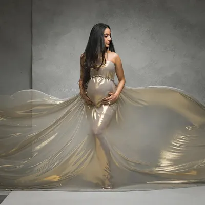A river of gold. This is one of my signature fine-art maternity portraits, using flowing metallic fabric and dramatic lighting to create a breathtaking, goddess-like image.