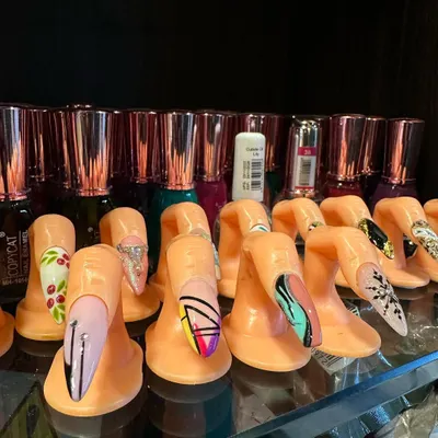 This image showcases a variety of advanced nail art designs created on practice fingers. You can see examples of geometric patterns, glitter accents, and intricate line work that you will learn to create in our courses.