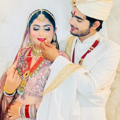 A beautiful moment between a bride and groom in their coordinated outfits from my studio. Her pastel lehenga is perfectly complemented by his ivory and gold sherwani.
