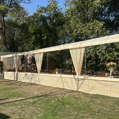 A beautiful daytime event setup in a lush green lawn. Our long, covered buffet station ensures food stays fresh while blending elegantly with the outdoor environment.
