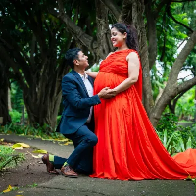 A classic pose that is always full of emotion. The father-to-be kneels to connect with his baby, while the mother-to-be, in a stunning red gown, looks on with love. This was taken in a beautiful green park, adding to the romantic feel.