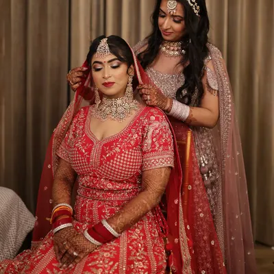 A sweet moment between sisters. The bride's sister helps with the final touches, adjusting the dupatta. It's these moments that make a wedding so special.